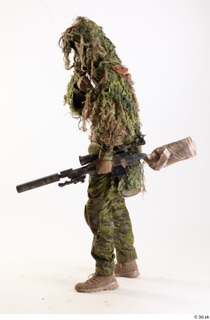 Andrew Elliott in Ghillie Pose with Gun holding gun standing…